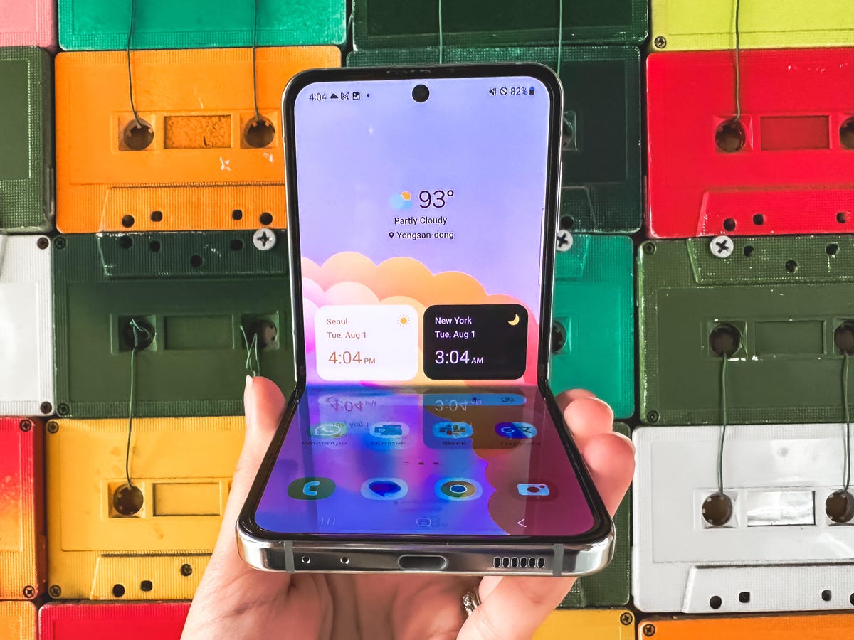 Samsung's Galaxy Z Flip 5 pictured half-open against a wall of colorful cassette tapes.