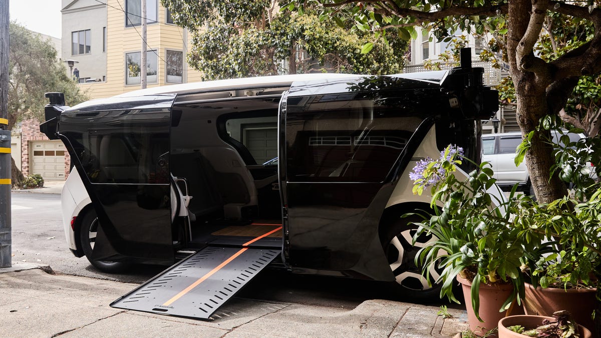 A Cruise wheelchair-accessible vehicle with the ramp down is parked in front of a driveway