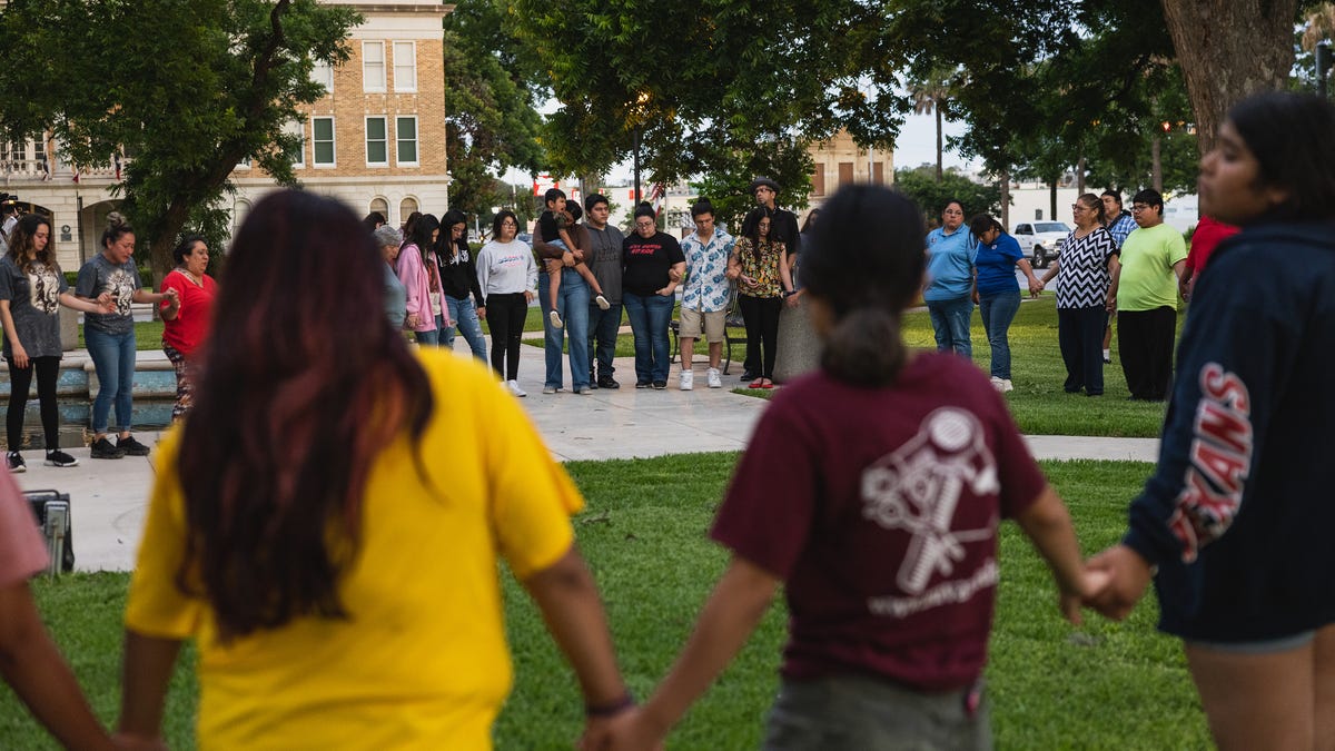 Members of the Uvalde, Texas, community holding hands in a circle after school shooting.