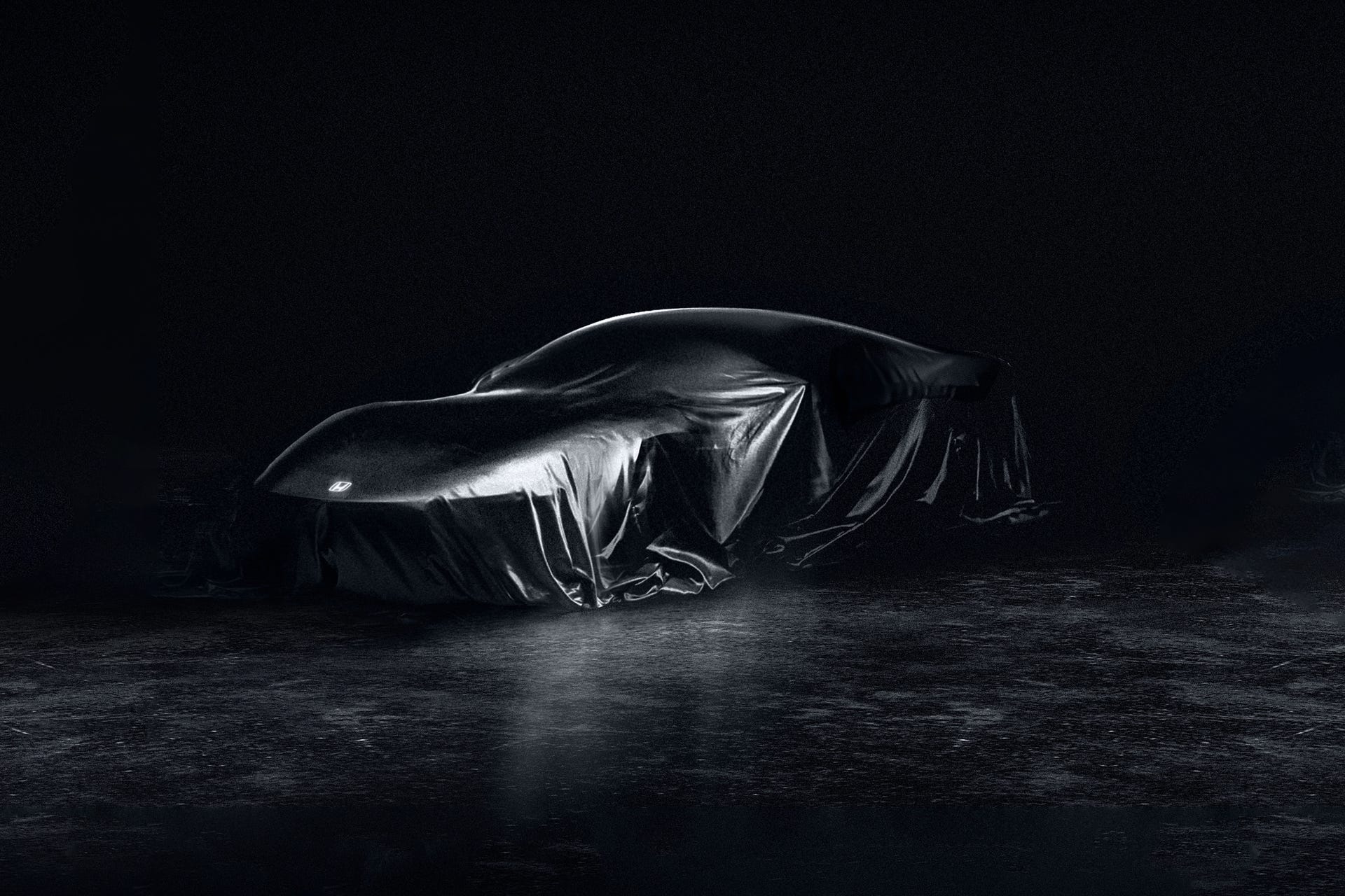 A black sports car from the side, against a dark background.