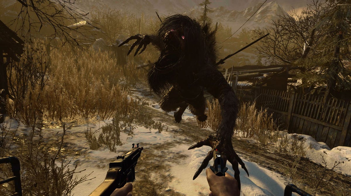 Two hands holding guns, attacking a shadowy monster in a snowy village in a video game called Resident Evil Village
