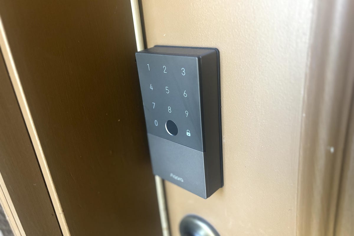 The Aqara U100 keypad installed on a brown door.