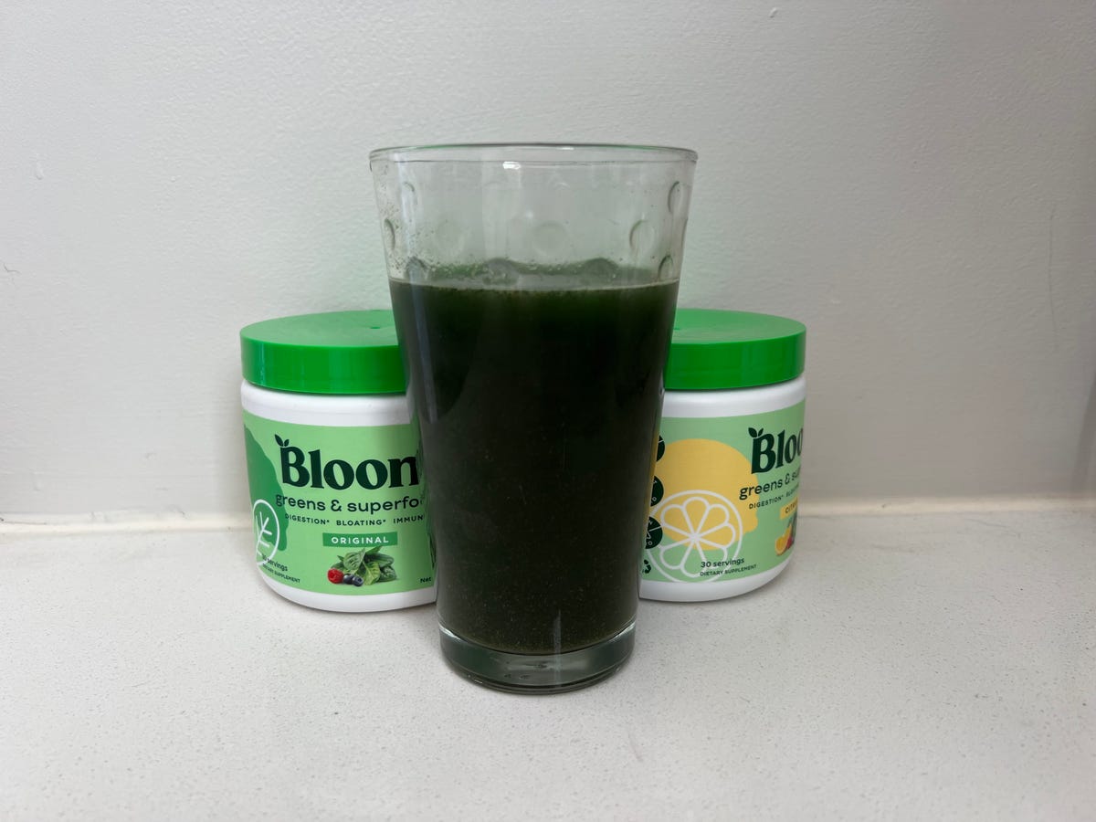 A cup of greens with two containers of Bloom flavors