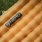 Image of orange camping air pad on grass
