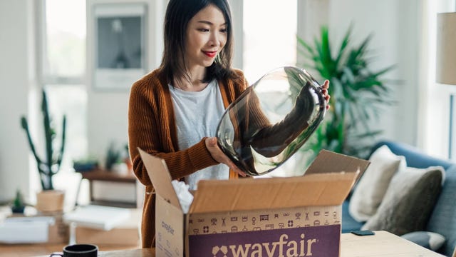 Woman removing glass vase from Wayfair shipping box