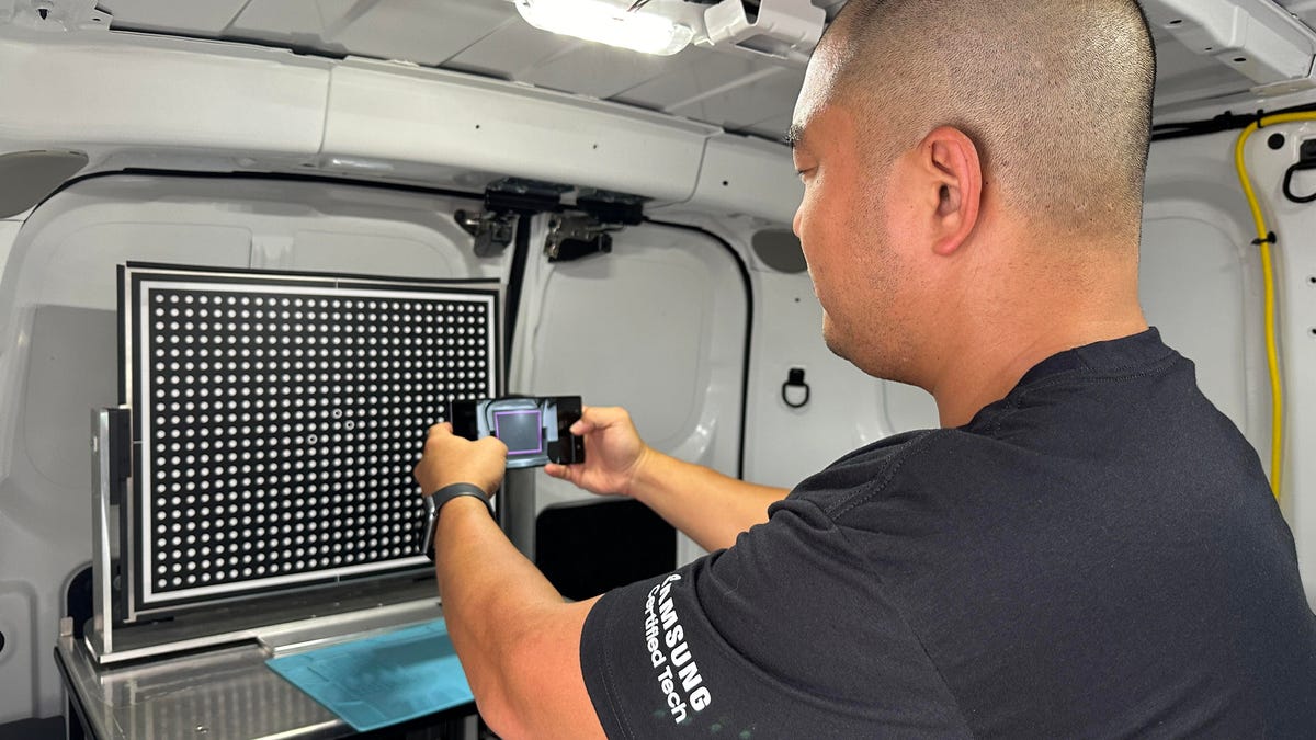 Man holding phone, running camera tests, inside of a van.