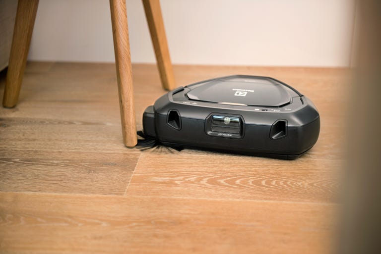 The triangular-shaped Electrolux Pure i9 robot vacuum navigates a hardwood floor.