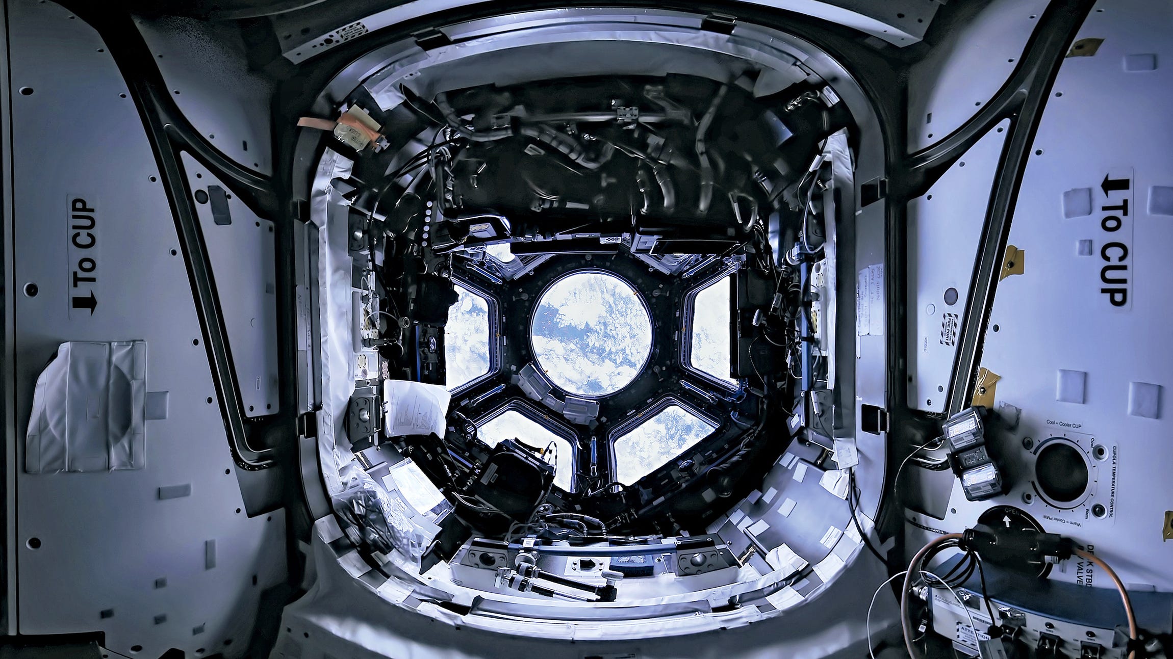 The ISS cupola window offers a glimpse of Earth with swirls of blue and white