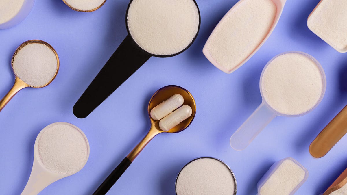 Many spoons with collagen powder and pills on the blue background.