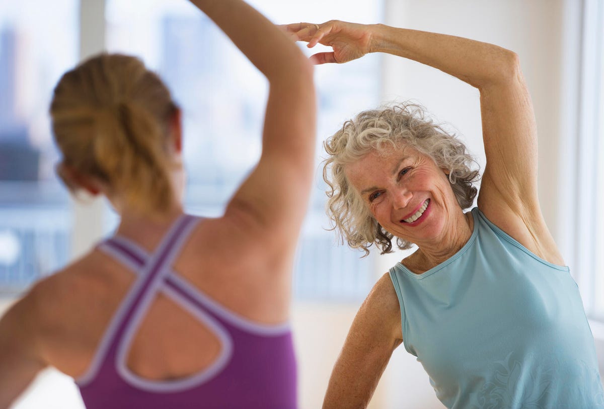 Mujer mayor con instructor de fitness en el gimnasio