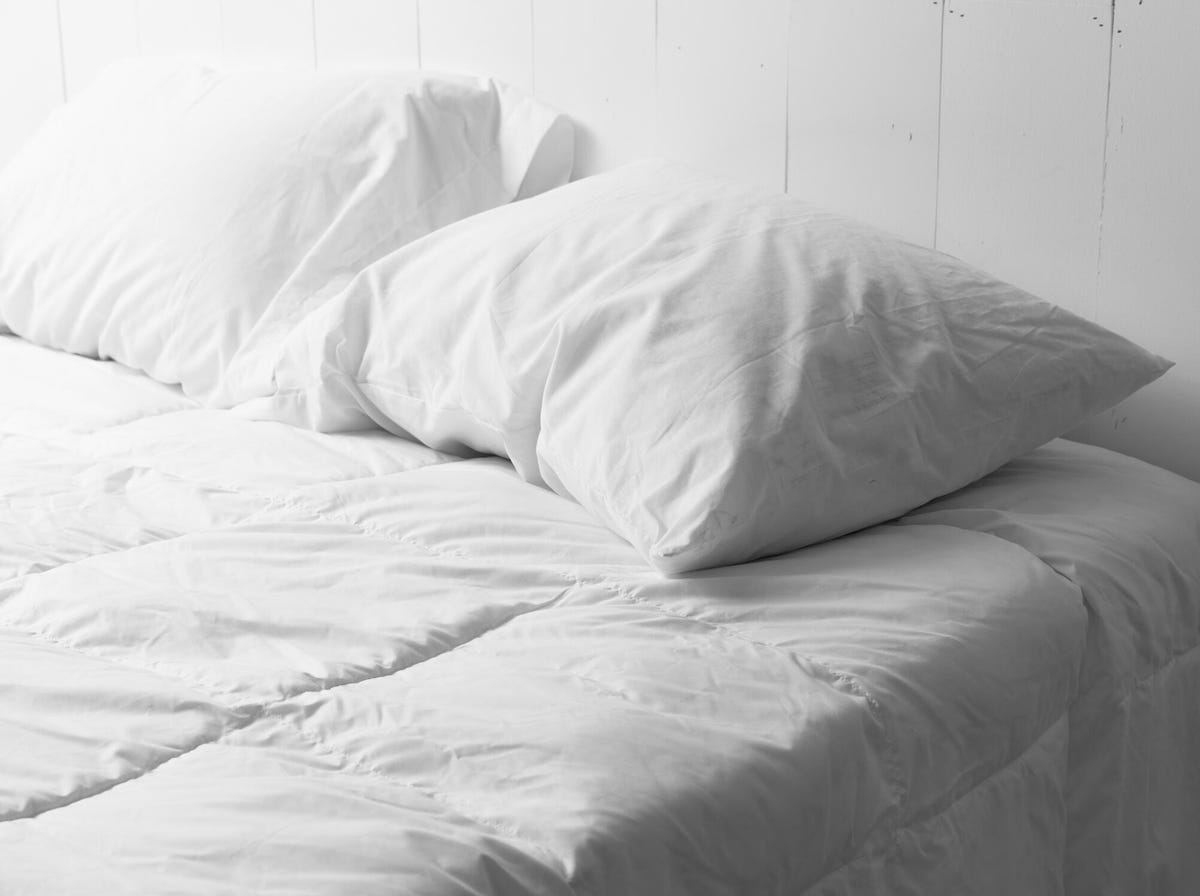 Two white pillows on a white comforter.