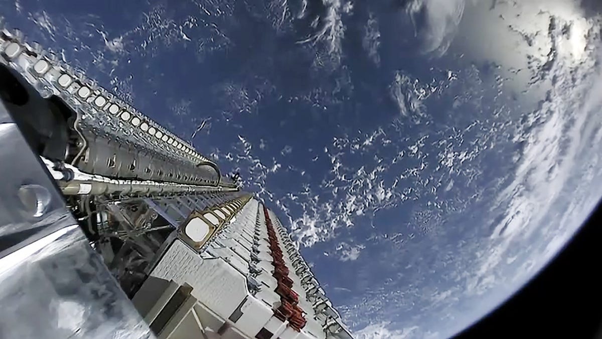 View from space shows blue Earth below and a partial view of Starlink satellites as they're deployed into orbit.