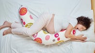 A pregnant person sleeping with a pregnancy pillow with orange and pink designs