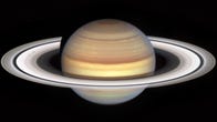 Saturn looks like a swirled beige, pink and yellow marble with light rings around it with some dark streaks and shadowy formations like little blotches (known as spokes).