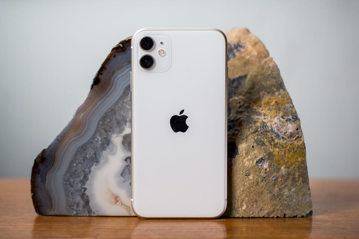 The iPhone 11 standing up on a table against a rock