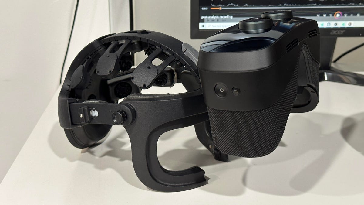 Prototype VR headset on a white table, with the visor flipped up.