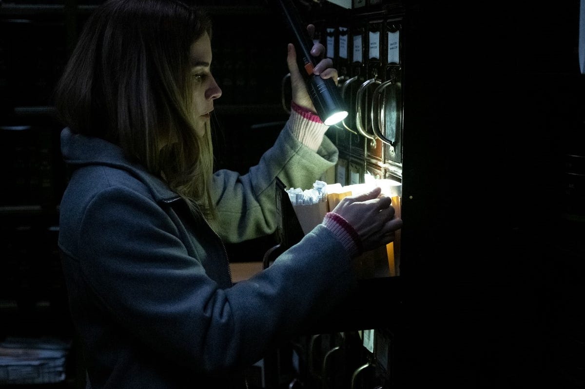 Alison searches a filing cabinet by flashlight.
