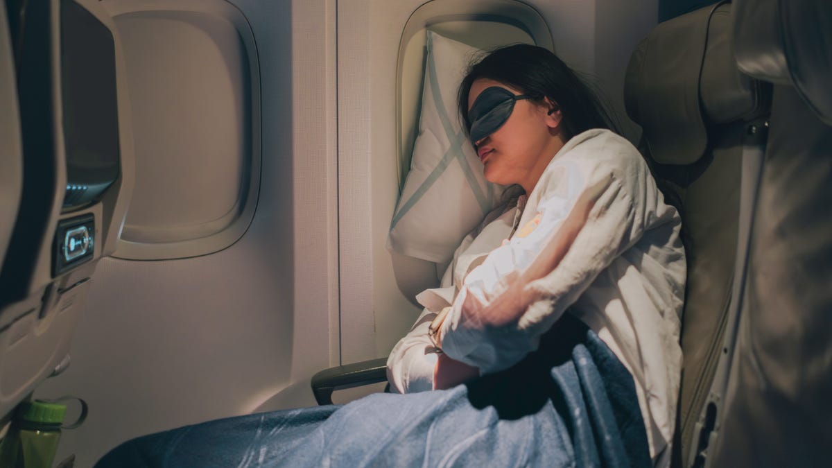 A woman sleeps while traveling on a plane. 