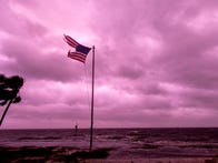 <p>A battered American flag flies against a purple sky&nbsp;</p>