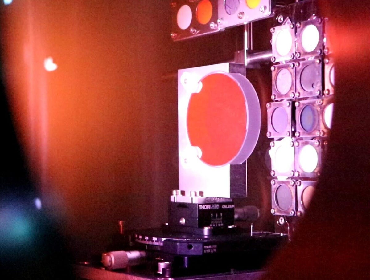 画像の左側全体を占める赤みを帯びた光線にさらされた、異なる物質のいくつかの円が見られます。