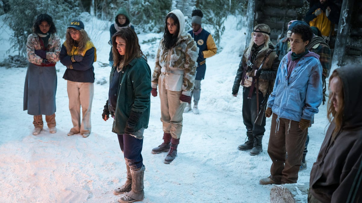 A group of teen girls stands in the snow, looking in the distance