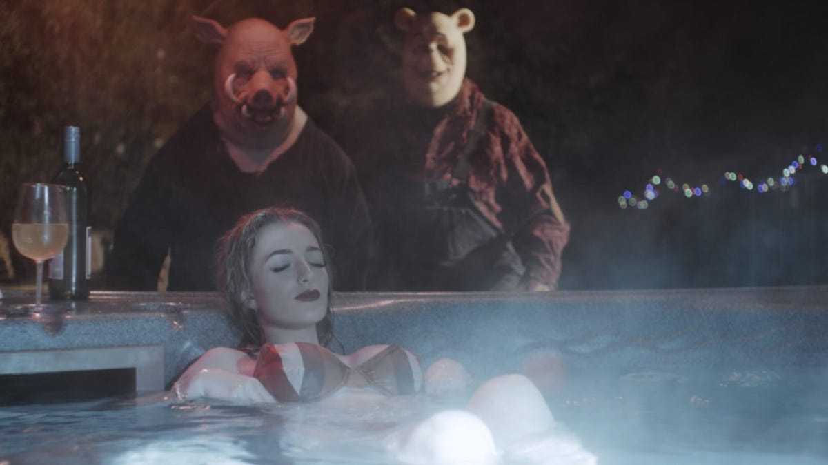 Scary figures wearing piglet and bear masks creep up on a woman in a hot tub.
