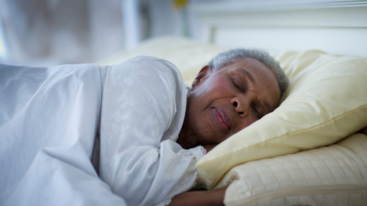 Older woman sleeping on her side with her head elevated on a stack of pillows