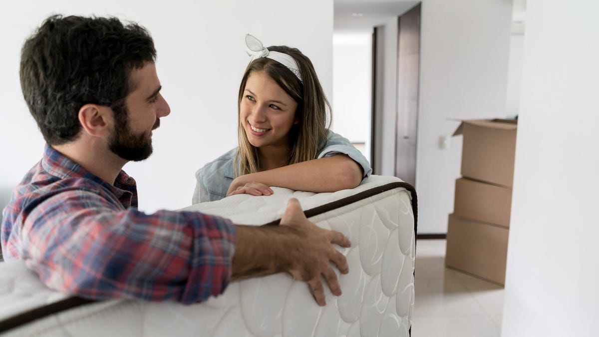 Man and woman talking while they are moving a new mattress into a bedroom