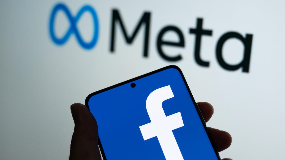 Facebook logo on a phone in front of Meta sign