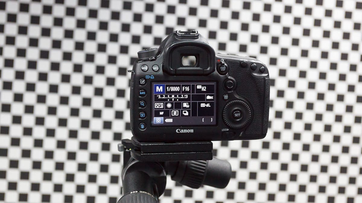 Canon's 5D Mark III is perched on a tripod in front of a chessboard pattern used to test its image sensor's ability to capture sharp images.