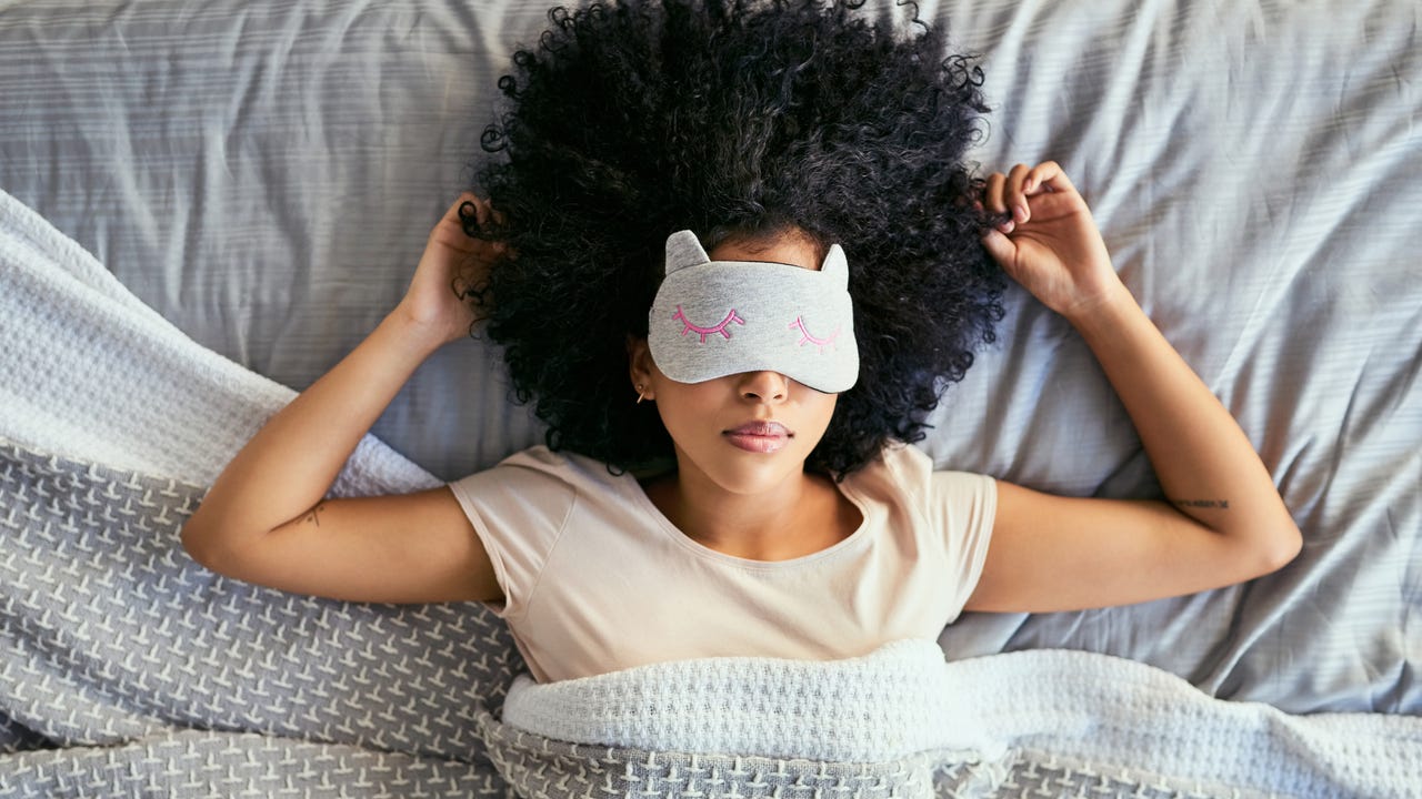 Woman sleeping on her back with a sleep mask on.