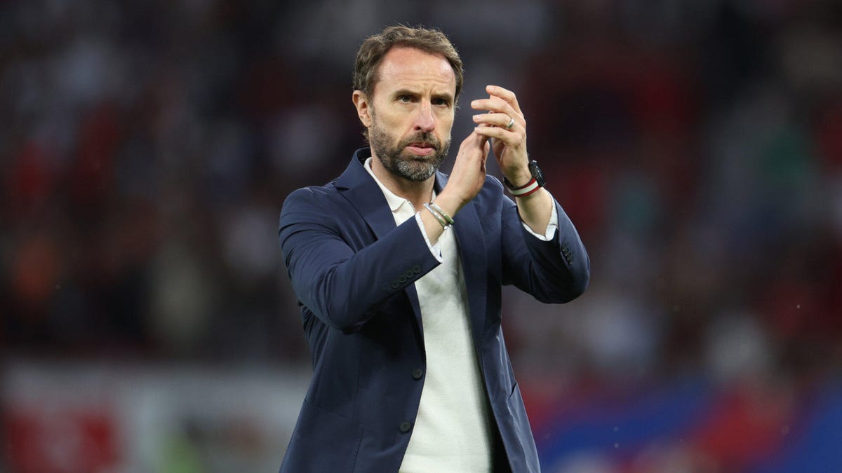 England soccer manager Gareth Southgate wearing a suit jacket and white shirt, applauding.