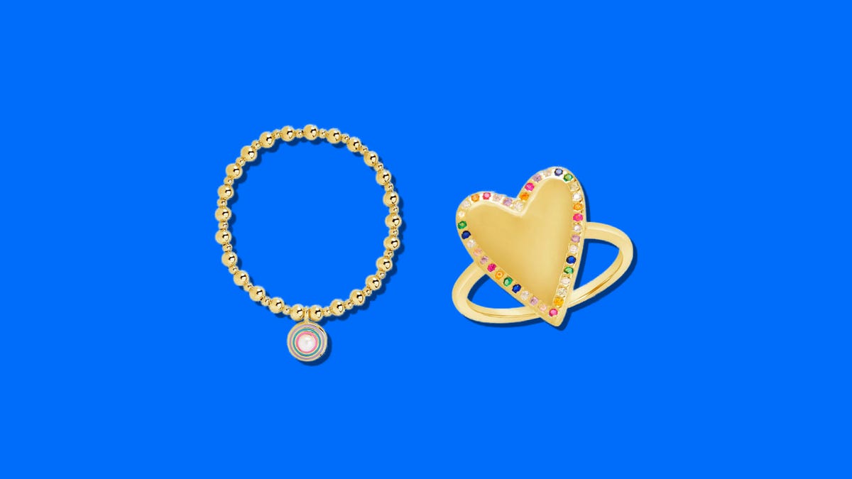 A gold bracelet and a gold ring with colorful stones on it side by side on a blue background