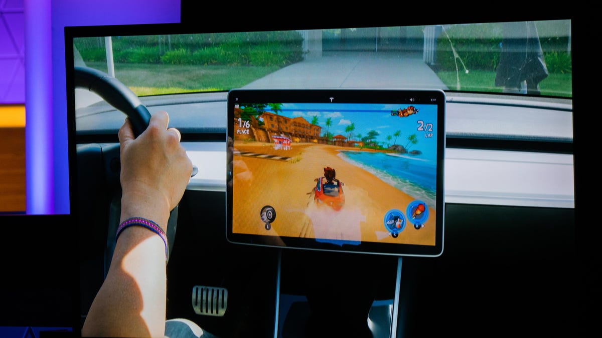 A tablet mounted to a car dashboard shows a beach buggy racing game on screen