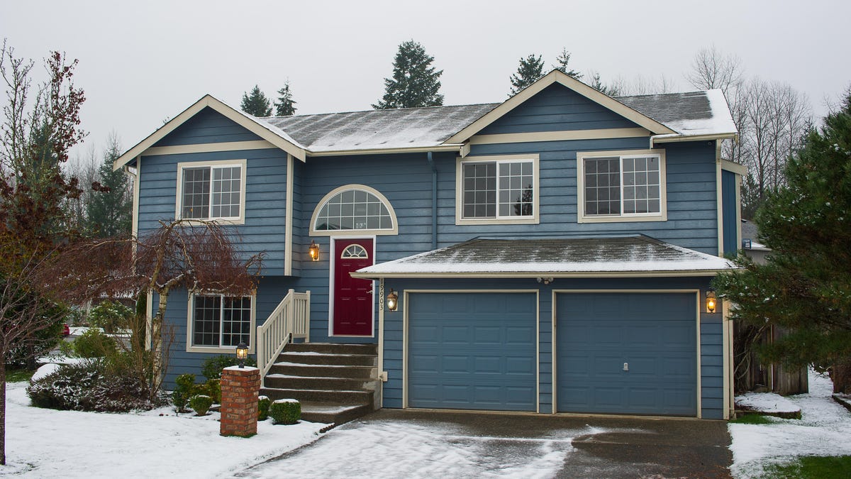 a blue home with a double garage dusted with snow
