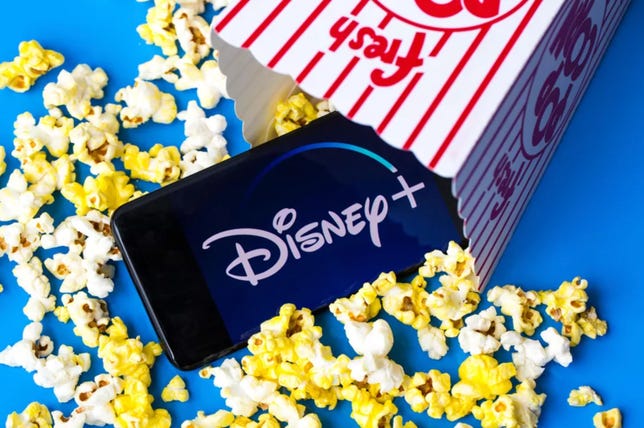 Disney Plus logo on a phone spilling out of a popcorn bag along with some popcorn