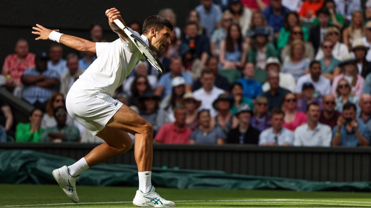 Tennis player Novak Djokovic attempting to hit the ball.