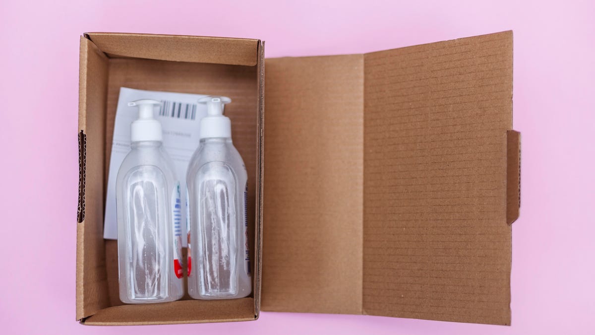 A box full of two medical bottles against a pink background