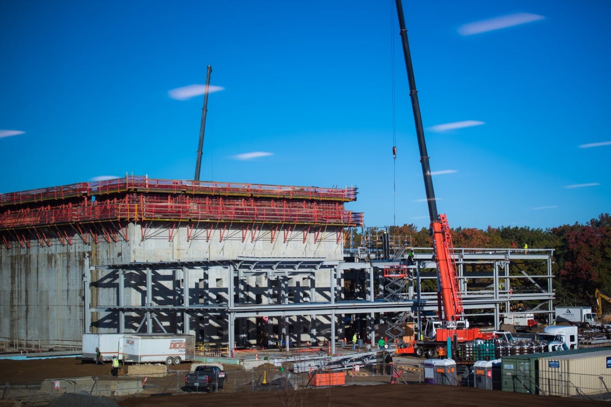 A crane helps construct a large concrete and steel building that will house Commonwealth Fusion Systems' Sparc reactor
