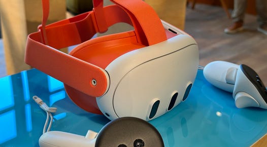 A Meta Quest 3 VR headset on a table, with orange straps