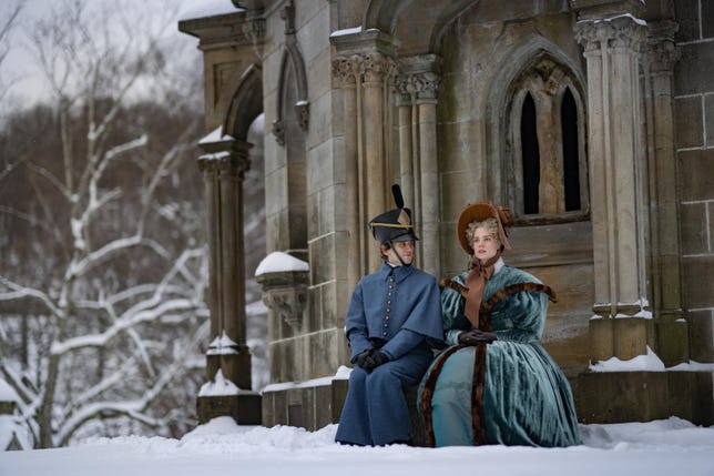 Edgar und Lea sitzen draußen im Schnee neben einem Gebäude
