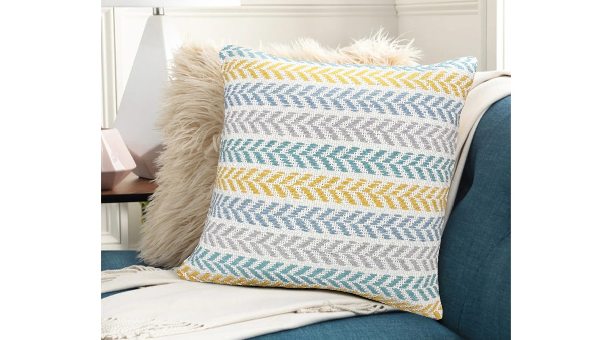 A gray, blue and yellow multicolored throw pillow on a dark blue couch.