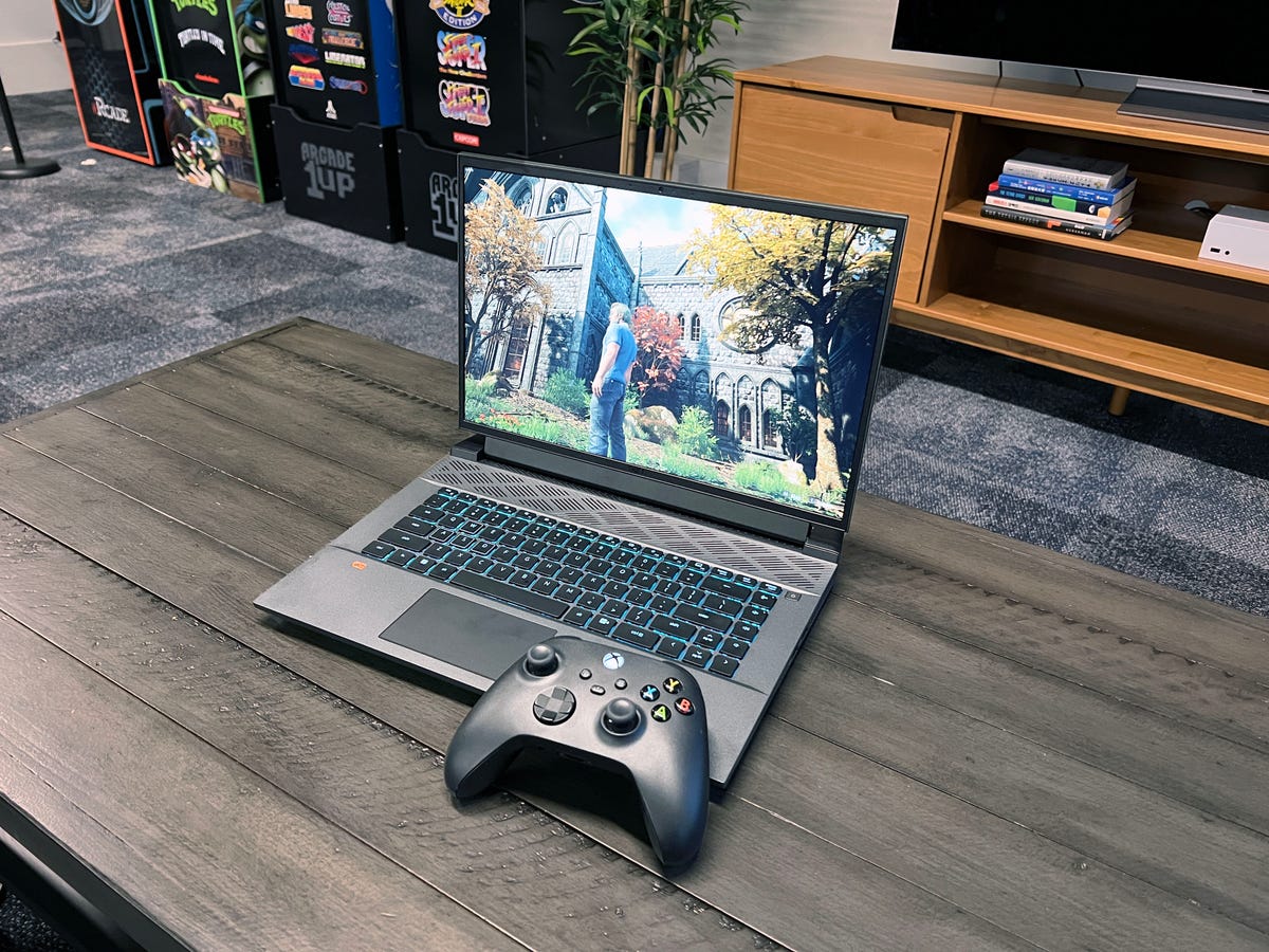 The Dell G16 laptop open on a coffee table with a gaming controller