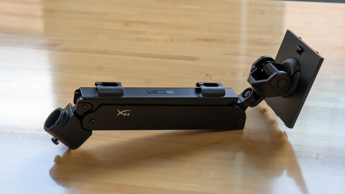 The mounting arm of the HyperX Armada 27 lying on a wood surface to show the cable-management clips