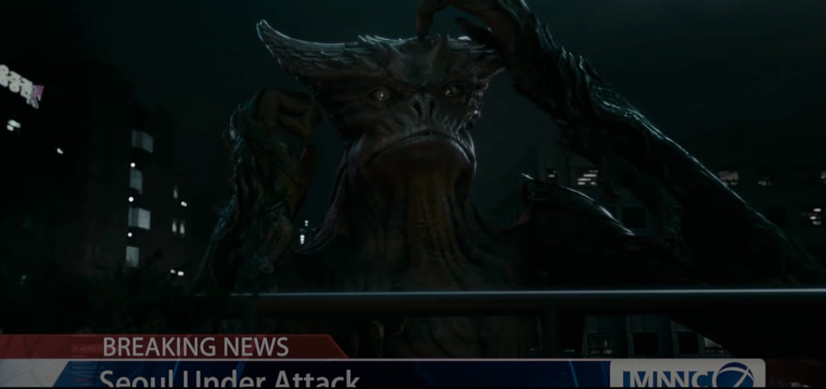 A giant reptilian creature scratches its head, shown on a news broadcast