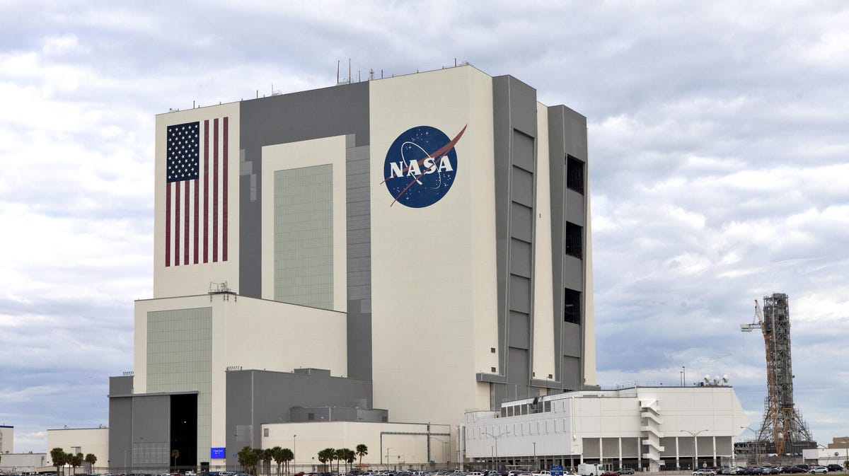 Tremendously huge building at Kennedy Space Center sports American flag and NASA meatball logo.