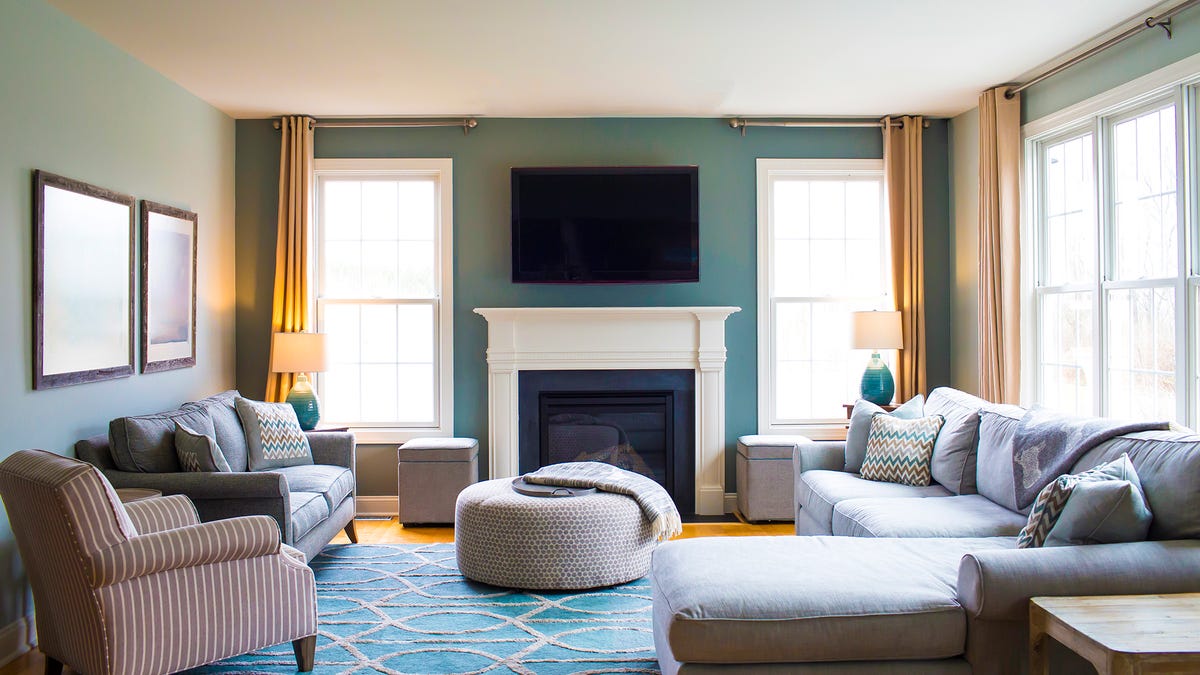Una sala de estar elegante y bien iluminada con muchas ventanas y un televisor montado sobre una chimenea.