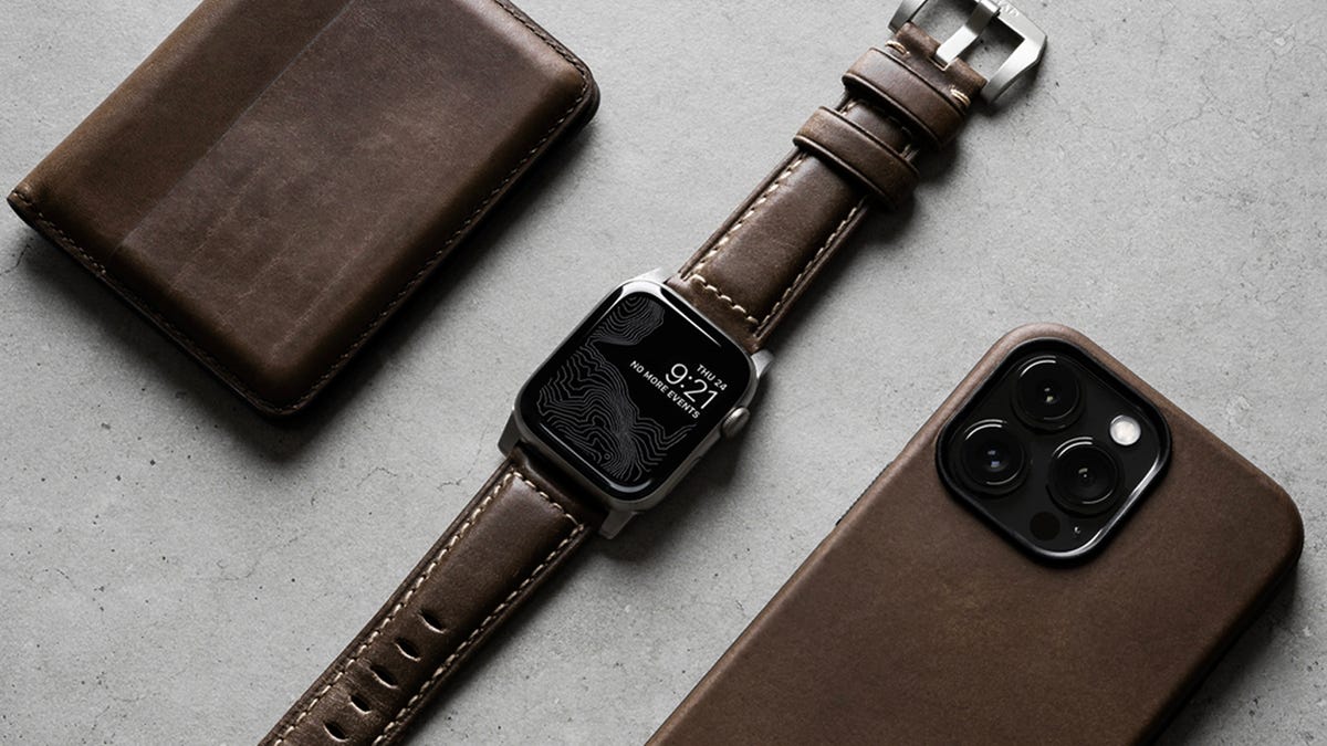 A brown leather Nomad wallet, Apple Watch Band and iPhone case.