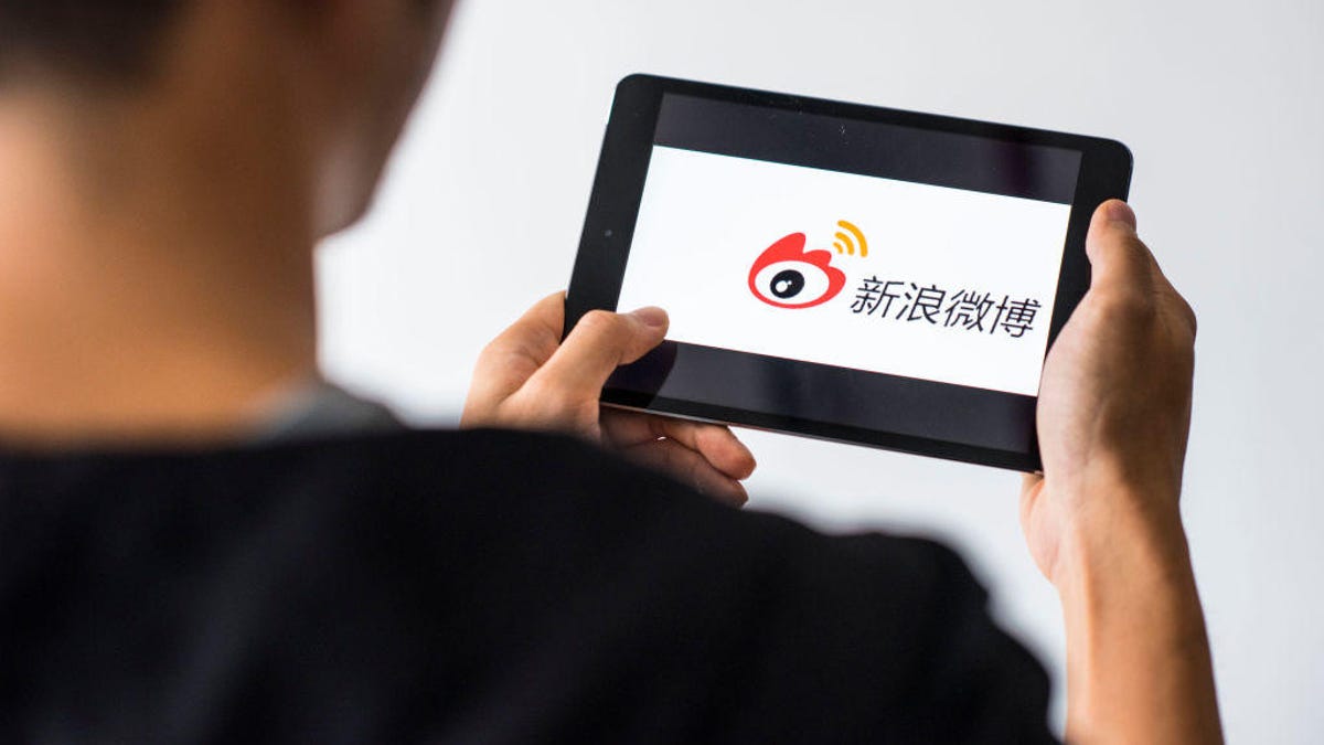 Young man holds a smart device while using Weibo app