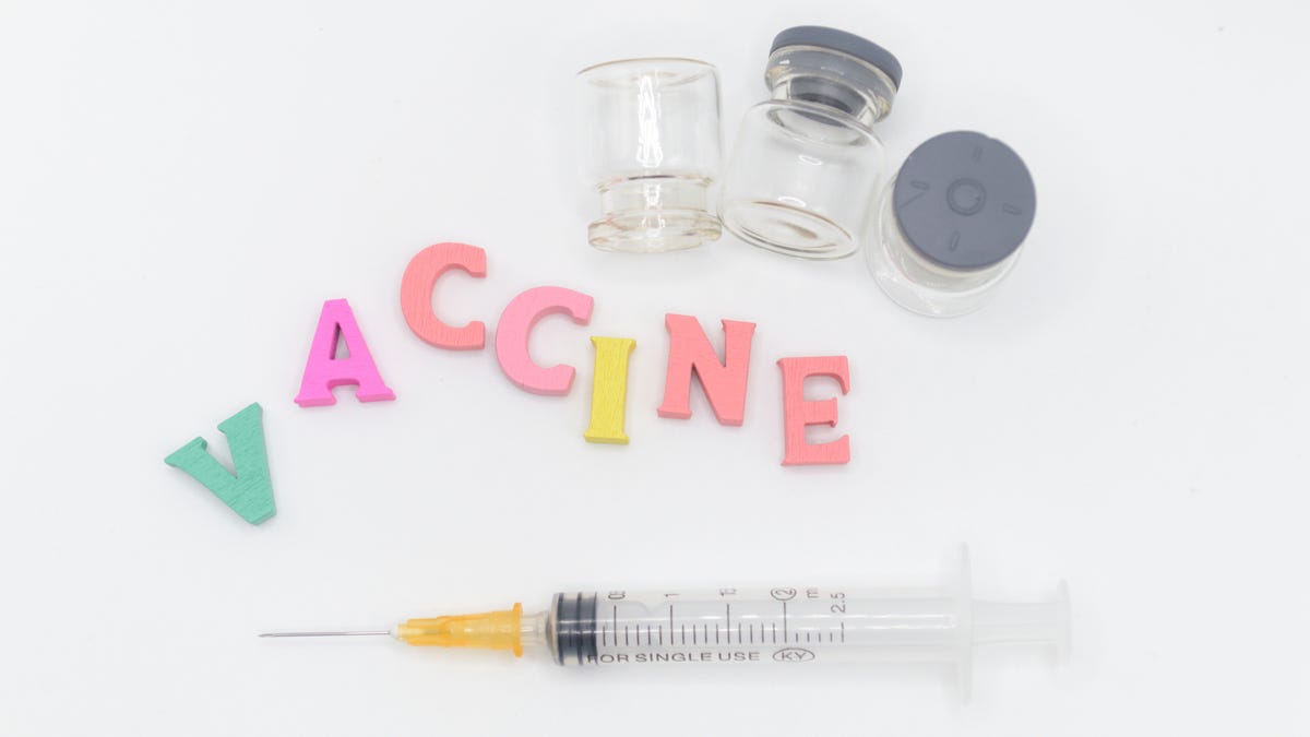 A hypodermic needle next to the word "vaccine" spelled out in colorful letters